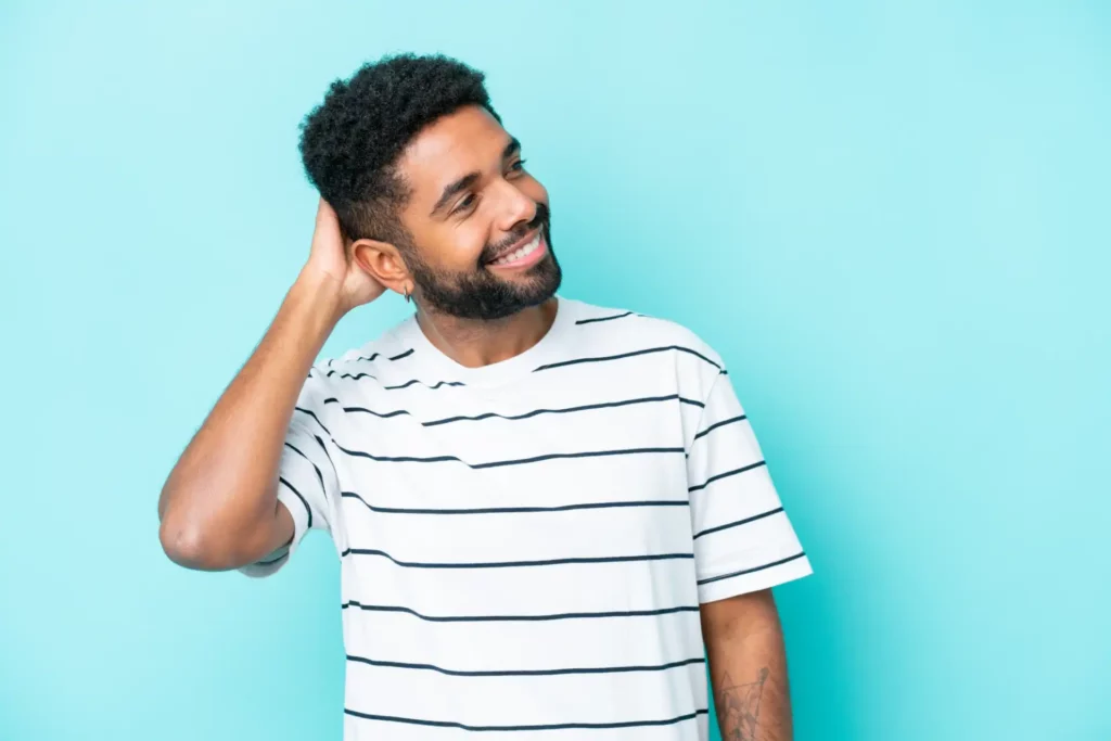 Homem sorrindo com camiseta listrada em fundo azul.