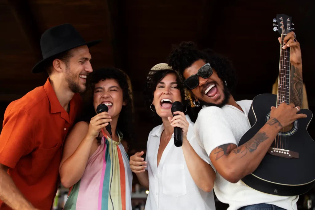 Quatro amigos se divertindo em uma apresentação musical ao ar livre, sorrindo enquanto cantam e tocam instrumentos, transmitindo alegria e energia positiva.