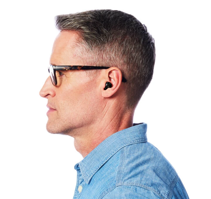 Homem usando oculos e fone de ouvido com cabelo curto e penteado moderno vestido com camisa de jeans azul em perfil lateral retrato de estilo casual